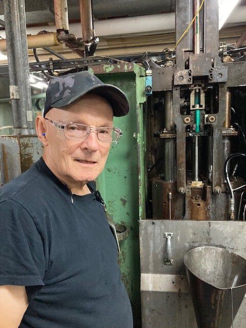 John Hollis standing in front of factory machine